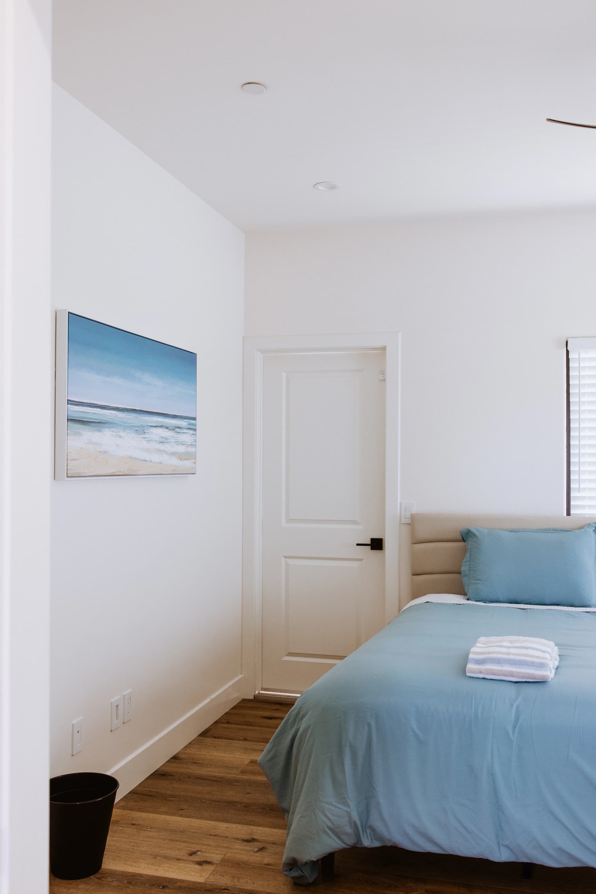 Private client bedroom with ocean artwork and comfortable bedding