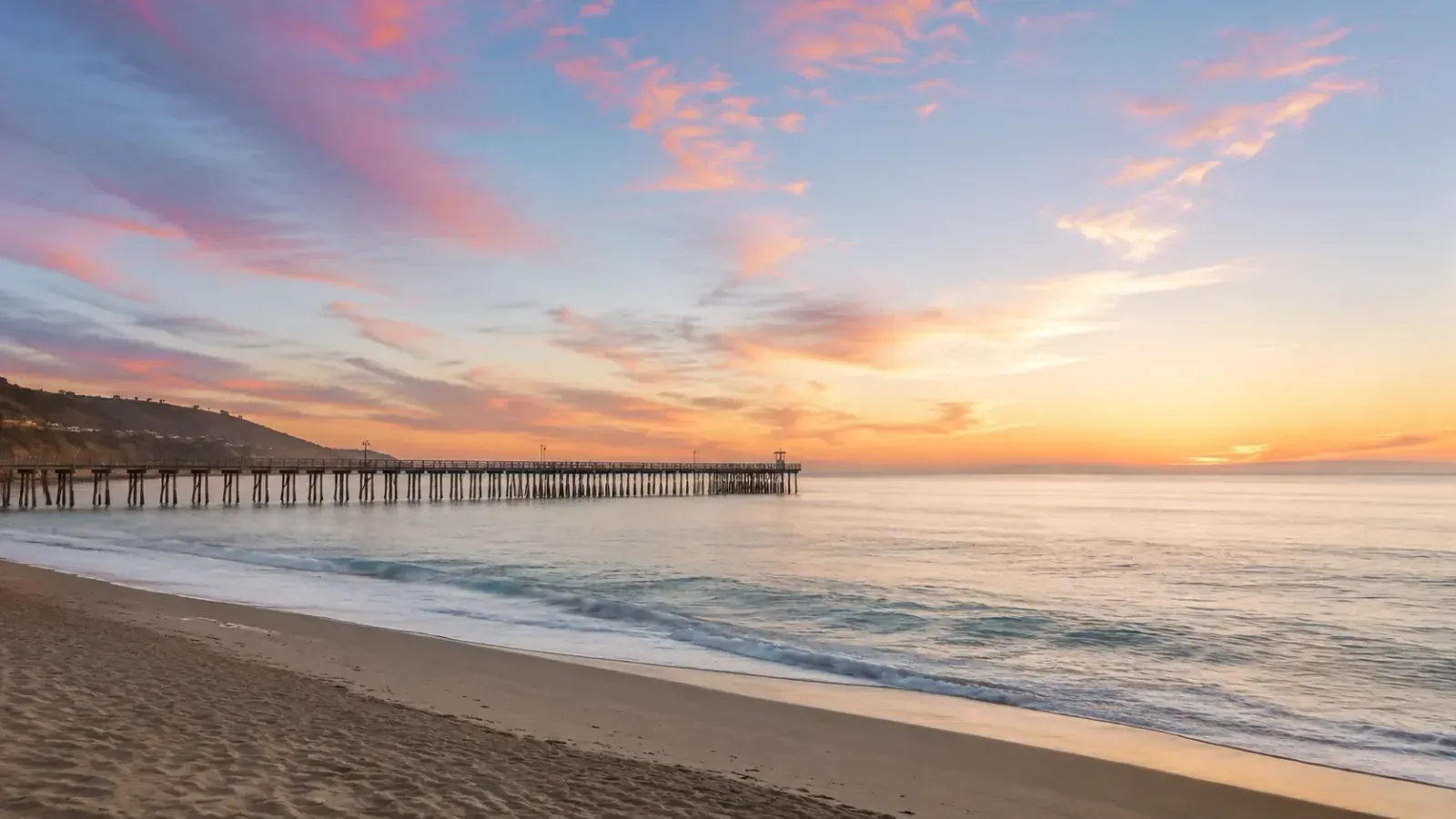 Wooden pier stretching into a calm ocean at sunset in Oceanside